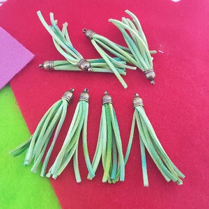 May include: Eight green and white leather tassels with bronze metal tops.