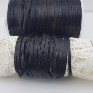 May include: A spool of black leather cord, wound tightly and ready for crafting projects.