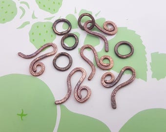 May include: A collection of copper wire jewelry findings, including jump rings and decorative loops. The findings are in various shapes and sizes, and have a rustic, hammered finish.
