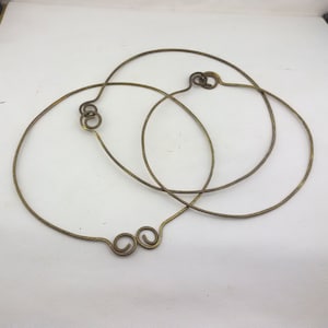 May include: Three gold-colored metal hoops with twisted ends. The hoops are intertwined.
