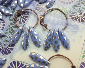 May include: A pair of copper hoop earrings with silver and blue teardrop-shaped beads. The beads have a polka dot pattern.