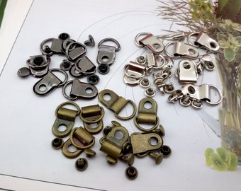 May include: Assortment of metal shoe eyelets and rivets in silver, black, and bronze. The eyelets are D-shaped and have a loop for attaching laces or straps. The rivets are small and have a flat head.