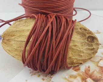 May include: A close-up of a reel of red leather cord. The cord is wound tightly around the reel and is ready to be used for crafting projects.