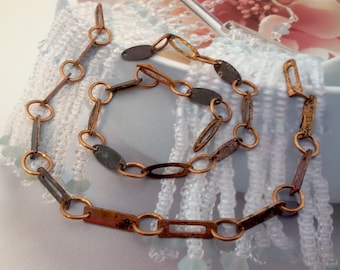 May include: A necklace and bracelet set featuring a rustic, antique design. The jewelry is composed of copper-colored metal links in various shapes, including circles, ovals, and rectangles. The metal has a weathered, aged appearance with dark accents.