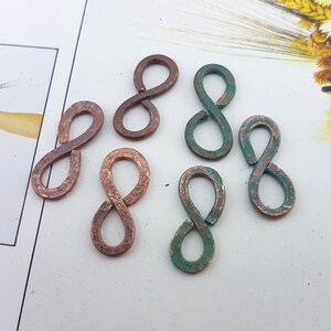 May include: Seven infinity symbol charms in copper with a green patina finish. The charms are all the same size and shape, but have different shades of green patina.