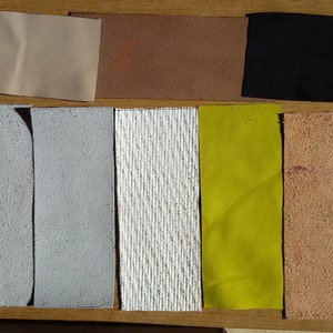 May include: A collection of ten fabric swatches in various colours and textures, including beige, brown, black, white, grey, yellow, and tan.