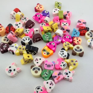May include: A collection of colorful animal-shaped beads, featuring a variety of designs including cats, dogs, pandas, and more. The beads are made of plastic and have a smooth, glossy finish.