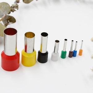 May include: Set of ten round metal hole punches with colorful plastic handles. The punches are arranged in order of size, with the largest punch on the left and the smallest punch on the right.