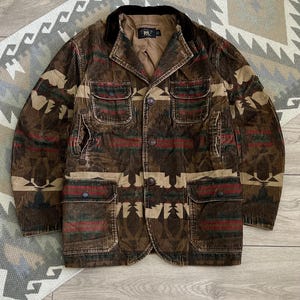 May include: A brown corduroy jacket featuring a multi-colored geometric pattern in shades of red, green, and tan. The jacket includes a dark brown velvet collar, four front flap pockets with button closures, and a button-front closure with an RRL label.
