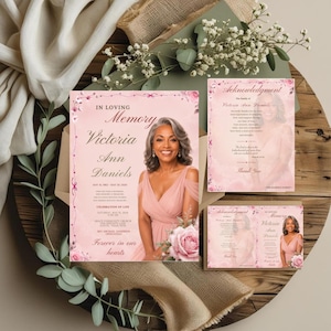 May include: A funeral program set featuring a soft pink background with floral accents. The main card displays the text In Loving Memory Victoria Ann Daniels, a photograph of a person, and event details. Includes an acknowledgment card and a folded card.
