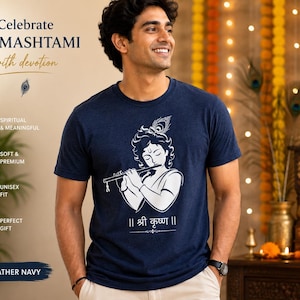 May include: A heather navy short-sleeve t-shirt featuring a white graphic print of Krishna playing a flute with a peacock feather in the hair. Below the graphic is the text "|| श्री कृष्ण ||". The shirt has a crew neckline and a standard fit.