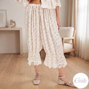 Può includere: Pantaloni corti dal taglio ampio color crema con un delicato motivo floreale di piccole dimensioni in tonalità tenui. Il capo presenta un girovita elasticizzato con coulisse e ampi orli a balze rifiniti con un intricato pizzo bianco.
