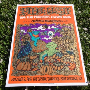 May include: A concert poster for Phil Lesh and the Terrapin Family Band featuring special guest Jimmy Herring. The poster is orange with a purple background and features a psychedelic illustration of a turtle, a bear, a crow, and sunflowers. The text "November 2, 2018 - The Capitol Theatre - Port Chester, NY" is at the bottom of the poster.