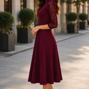 Puede incluir: Un vestido midi color burdeos con mangas de encaje de tres cuartos, cuello alto y falda acampanada. La prenda est&aacute; confeccionada con un cuerpo de color s&oacute;lido y detalles de encaje a juego en las mangas, combinado con zapatos de tac&oacute;n negros.