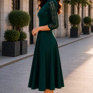 Puede incluir: Un vestido midi de color verde oscuro con mangas de encaje de tres cuartos, cuello alto y falda acampanada. La prenda se combina con zapatos de tac&oacute;n alto negros, creando un conjunto coherente con un cuerpo liso y detalles de encaje floral.