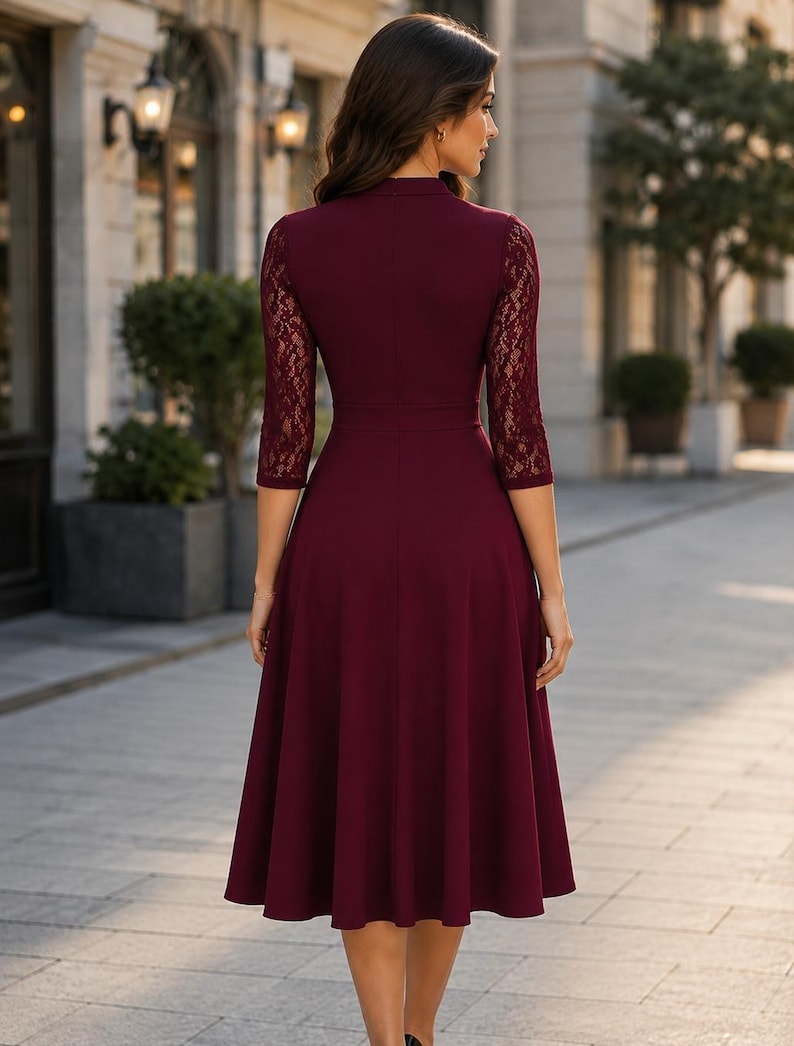 Puede incluir: Un vestido color burdeos hasta la rodilla con mangas de encaje de tres cuartos, cuello alto y un corpi&ntilde;o ajustado que se transforma en una falda acampanada. La prenda es de color s&oacute;lido con detalles de encaje floral en las mangas.