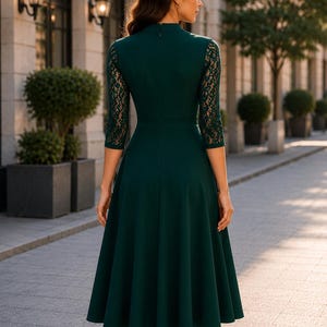 Puede incluir: Un vestido midi de color verde oscuro con cuello alto, mangas tres cuartos con detalles de encaje intrincados y una falda acampanada. La parte posterior del vestido incluye una cremallera oculta, lo que proporciona una silueta limpia y estructurada.