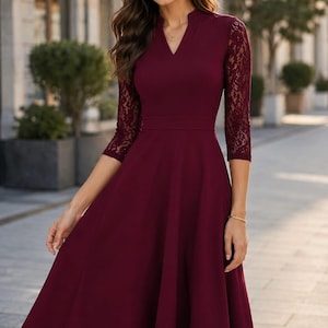 Puede incluir: Un vestido midi color burdeos con escote en V, cuerpo entallado y mangas tres cuartos de encaje floral intrincado. La falda es acampanada y llega por debajo de las rodillas, creando una silueta estructurada con un acabado de color s&oacute;lido.