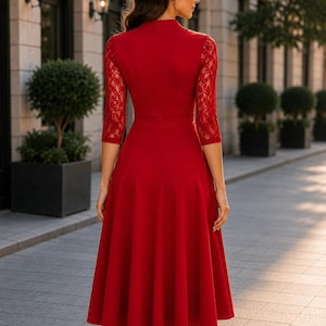 Puede incluir: Un vestido midi rojo con cuello alto, mangas tres cuartos con detalles de encaje intrincados y falda acampanada. La prenda tiene un corpi&ntilde;o ajustado que se transforma en una falda plisada y fluida, ofreciendo una silueta estructurada.