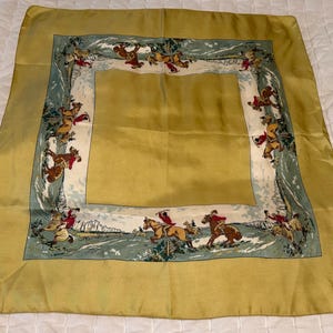 May include: A square scarf featuring a solid mustard yellow border and a central panel. The inner frame displays a repeating illustration of figures in red jackets riding horses across a landscape with muted green and white tones.