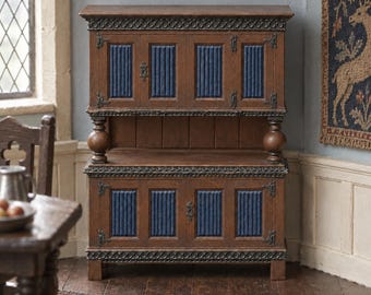 May include: A brown wooden cabinet featuring two levels with four doors total. Each door has a vertical blue ribbed panel insert. The cabinet includes dark metal hinges, decorative carved trim along the top and middle edges, and two spherical supports.