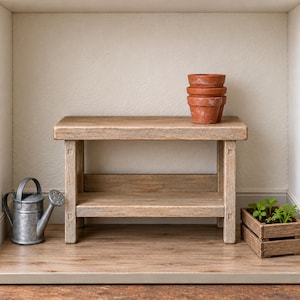 May include: A light brown wooden bench with two tiers and four legs. On the top tier sits a stack of three terracotta pots. To the left of the bench is a small silver metal watering can, and to the right is a small wooden crate with green plants.