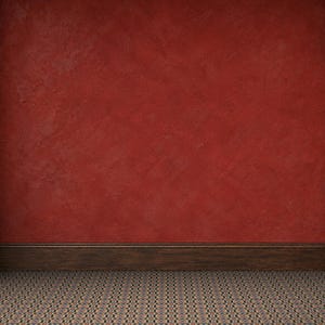 Pode incluir: Um interior de sala com uma parede vermelho-profundo com acabamento de gesso texturizado, um rodapé de madeira castanho-escuro que corre horizontalmente na base e um chão coberto por azulejos de padrão geométrico em tons suaves.