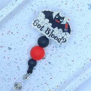 May include: A black and red beaded retractable badge holder with a glitter bat charm that says "Got Blood?"