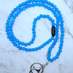 May include: A light blue beaded lanyard with a silver swivel clasp and a black plastic breakaway clasp.