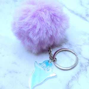 Op de afbeelding: Een paarse, pluche pompon sleutelhanger met een heldere, regenboogkleurige spookbedel bevestigd aan een zilveren sleutelring.