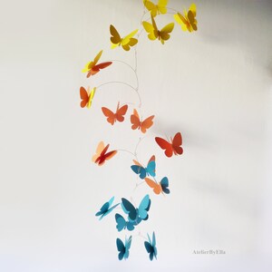May include: A mobile with butterflies in shades of yellow, orange, and blue. The butterflies are suspended from a wire and hang in a cascading pattern. The mobile is a whimsical and colorful decoration for a child's room.