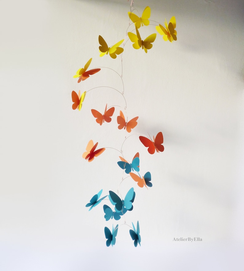 May include: A mobile with butterflies in shades of yellow, orange, and blue. The butterflies are suspended from a wire and hang in a cascading pattern. The mobile is a whimsical and colorful decoration for a child's room.
