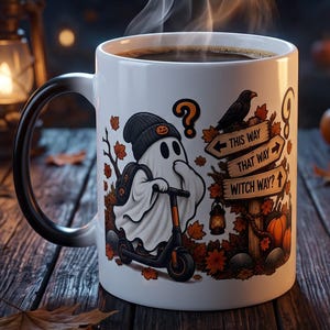 May include: A white ceramic mug filled with a steaming dark beverage, featuring a graphic of a ghost wearing a beanie on a scooter, a raven, and a wooden signpost with the text THIS WAY, THAT WAY, and WITCH WAY, surrounded by autumn leaves.
