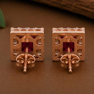 Peut inclure: Une paire de boucles d'oreilles carr&eacute;es dot&eacute;es d'une monture en m&eacute;tal dor&eacute; rose au design g&eacute;om&eacute;trique ajour&eacute;. Chaque boucle d'oreilles pr&eacute;sente une pierre pr&eacute;cieuse rouge fonc&eacute; de taille carr&eacute;e avec une tige et un fermoir papillon assortis.
