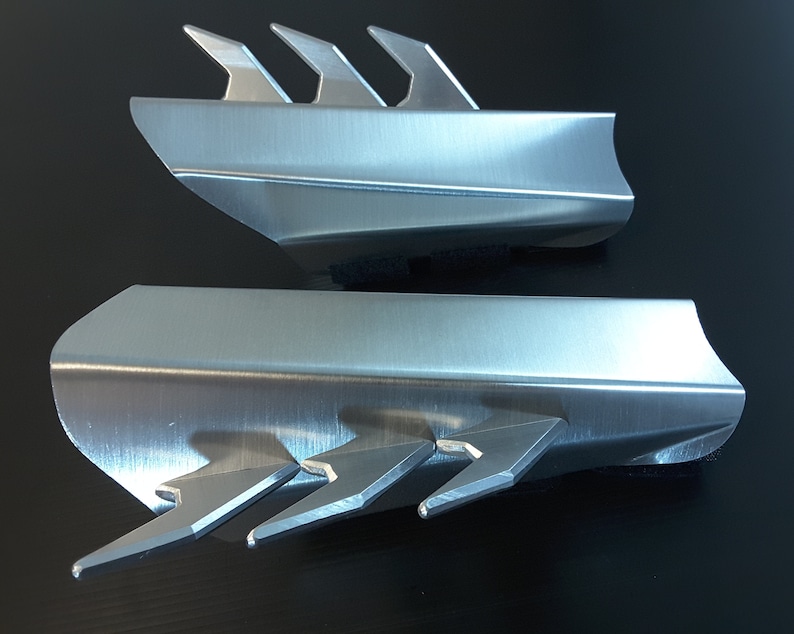 May include: Two silver metal pieces with a sharp, pointed design. The pieces are made of brushed metal and have a sleek, modern look.
