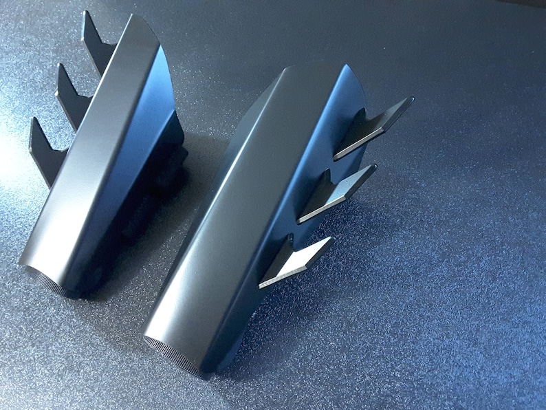 May include: Two black metal decorative pieces with a sharp, angular design. Each piece has a series of pointed protrusions along one edge.