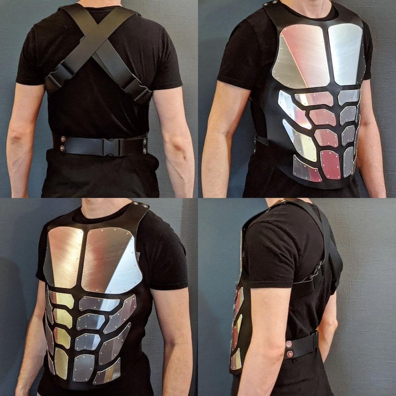 May include: A silver and black chest plate with a textured design. The chest plate has a black leather strap across the back.