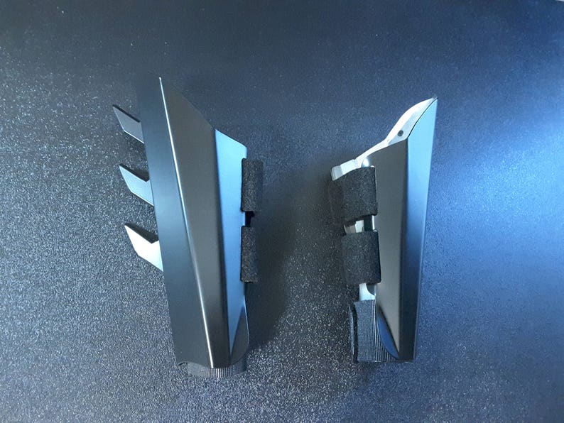 May include: Two black plastic pieces with a triangular shape and a textured surface. The pieces have a series of small, sharp points on one side.