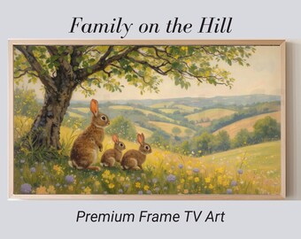May include: A framed landscape painting titled "Family on the Hill" shows three brown rabbits under a tree, overlooking rolling green hills. The artwork features yellow and purple wildflowers and is labelled "Premium Frame TV Art."