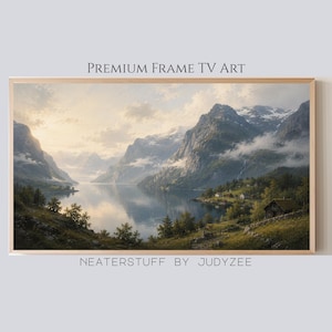 Op de afbeelding: Een ingelijst landschapsschilderij toont een serene meeromgeving met bergen. Het kunstwerk gebruikt een natuurlijk kleurenpalet met zachte blauwen, groenen en witten. De tekst "PREMIUM FRAME TV ART" en "NEATERSTUFF BY JUDYZEE" zijn zichtbaar.
