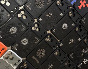 Puede incluir: Una colección de fundas para smartphone con diversos diseños, incluyendo superficies negras con textura de cuero y emblemas de cruz de metal plateado, fundas de color naranja vibrante y fundas negras adornadas con patrones de cruces coloridas.