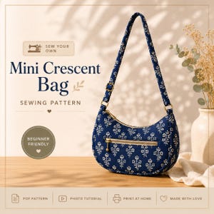 May include: A navy blue mini crescent bag with a white floral pattern, featuring a single shoulder strap, a gold-tone zipper closure, and an exterior zippered pocket. The text reads: Sew Your Own, Mini Crescent Bag, Sewing Pattern, Beginner Friendly, PDF Pattern, Photo Tutorial, Print at Home, Made with Love.