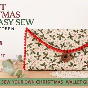 Puede incluir: Una cartera de tela rectangular con un estampado navideño de hojas de acebo, bayas y bastones de caramelo. La cartera tiene una solapa triangular, ribete de pompones rojos en los bordes y un botón de madera marrón oscuro.
