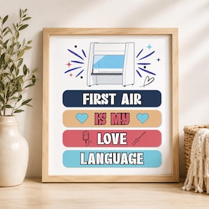 May include: A framed print featuring a white laminar flow hood illustration above the text "FIRST AIR IS MY LOVE LANGUAGE" on four colored bars, with blue hearts, an IV bag, and a syringe icon integrated into the design.