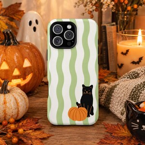 May include: A smartphone case featuring a vertical wavy pattern in light green and white. The design includes a black cat sitting next to an orange pumpkin. The case has a black camera cutout at the top left corner and a smooth, matte finish.