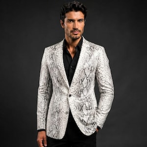 May include: A blazer featuring a white and grey snakeskin pattern with a single button closure, notched lapels, and two flap pockets, worn over a solid black button-down shirt. The garment has long sleeves and a structured, tailored fit.