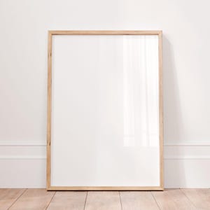 May include: A vertical rectangular picture frame with a light-toned natural wood finish. The frame features a clean, simple design with a smooth surface and a clear glass front, enclosing a blank white rectangular space for display purposes.
