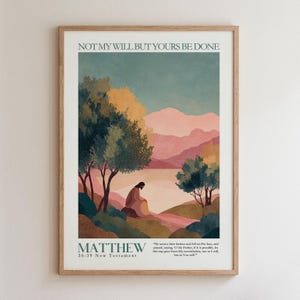 May include: A framed wall art print featuring a landscape illustration with a figure sitting under trees. The text reads NOT MY WILL BUT YOURS BE DONE, MATTHEW 26:39 New Testament, and a passage. The scene includes pink mountains and green foliage.