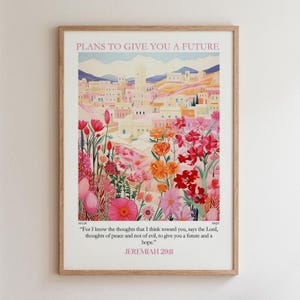 May include: A framed wall art print featuring a landscape of a desert town in soft pastel tones, surrounded by vibrant pink, orange, and red wildflowers. The text reads: PLANS TO GIVE YOU A FUTURE and For I know the thoughts that I think toward you, says the Lord, thoughts of peace and not of evil, to give you a future and a hope. JEREMIAH 29:11.