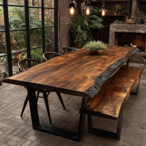 Puede incluir: Una mesa de comedor rectangular grande y un banco a juego, ambos con tableros de madera natural de borde vivo con vetas de color marrón oscuro, sostenidos por patas de metal negro en forma de U. Un cuenco con una planta verde está sobre la mesa.